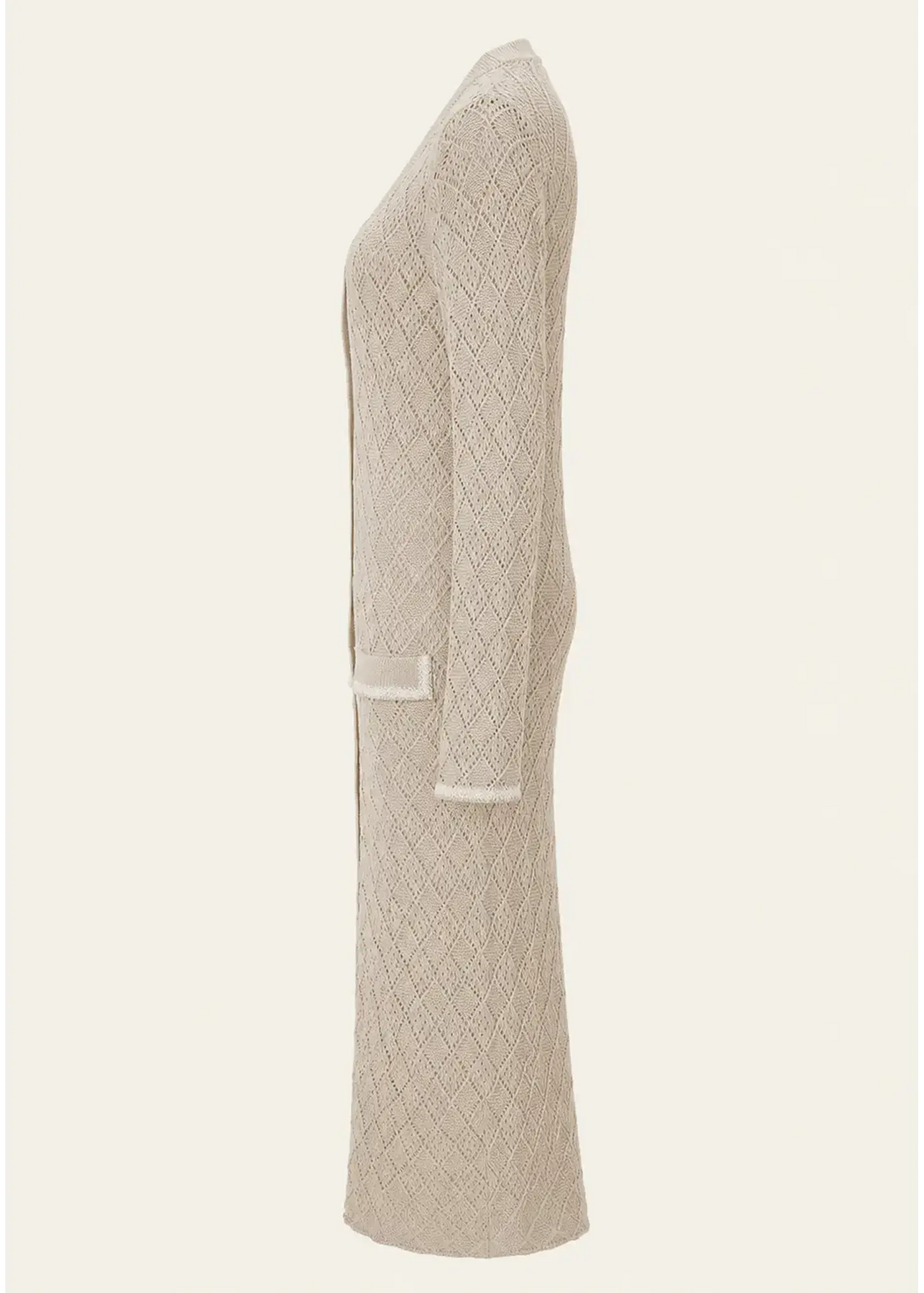 Side view of a luxury women's knit cardigan dress crafted from fine cotton, featuring an intricate diamond-knit pattern, long sleeves, patch pockets, contrast trim detailing, and a flowing ankle-length silhouette in a soft natural beige tone.
