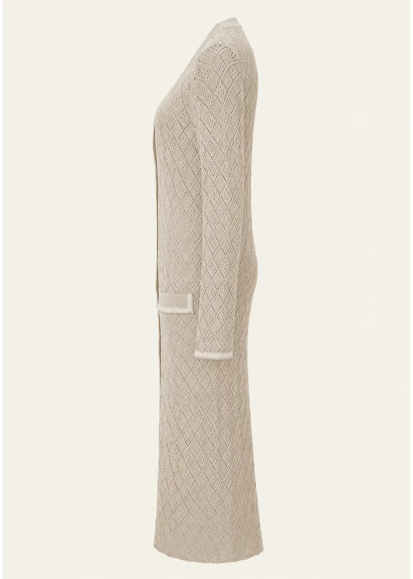 Side view of a luxury women's knit cardigan dress crafted from fine cotton, featuring an intricate diamond-knit pattern, long sleeves, patch pockets, contrast trim detailing, and a flowing ankle-length silhouette in a soft natural beige tone.
